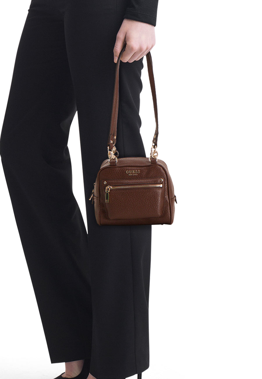 Sac à bandoulière marron Guess® avec logo proéminent, fermetures éclair dorées et texture grainée, porté sur le côté.