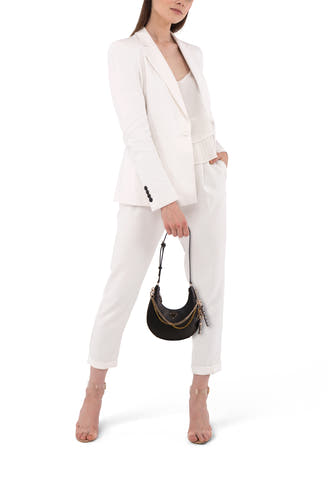 Sac à dos noir de Guess, avec détail de chaîne en or, porté avec un short blanc et des bottes transparentes.