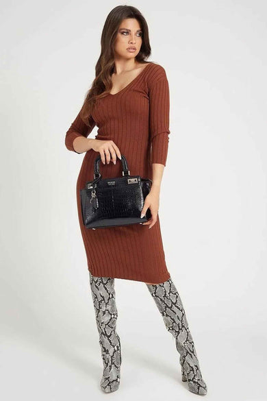 Sac à dos noir de Guess avec un imprimé crocodile et un mousqueton décoratif ; le modèle porte une jupe brune et des bottes en cuir de serpent.