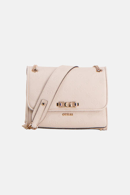 Sac à bandoulière blanc Guess, avec une bandoulière chaîne dorée, porté par un mannequin dans un col roulé noir et un pantalon avec talons.