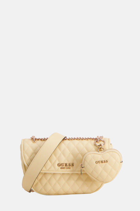 Geelkleurige Guess tas met ketting en hartvormige accessoire.