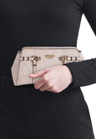 Sac à bandoulière beige Guess® avec motif monogramme G intégral, détails de boucle dorée et fermeture à glissière, tenu devant une tenue noire.