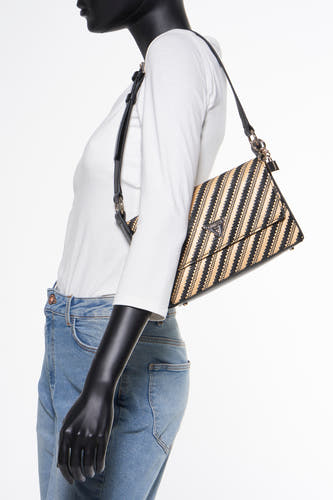 Sac à dos noir de Guess, avec un motif tressé en paille et des détails noirs, porté sur une chemise blanche et des jeans bleus.