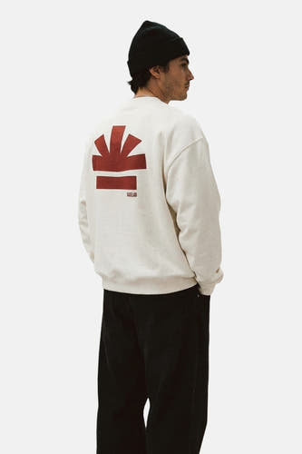 Witte sweater van BASELAB, met rode print op de rug, gedragen met een zwarte muts en wijde zwarte broek.