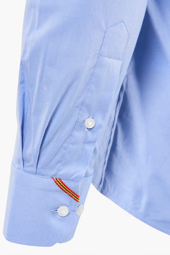 Chemise bleue à manches longues de Le Fabuleux Marcel de Bruxelles, détail de la patte de boutonnage avec des boutons et une bande décorative.