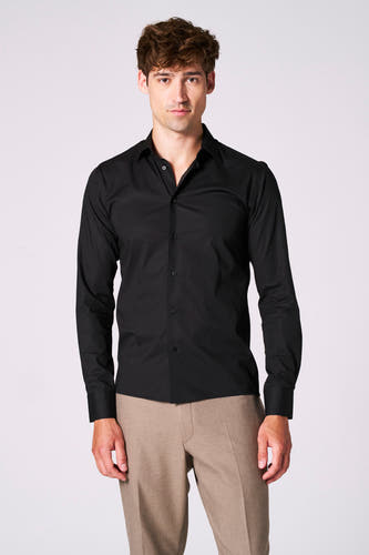 Chemise noire à manches longues de Le Fabuleux Marcel de Bruxelles, portée avec un pantalon marron.