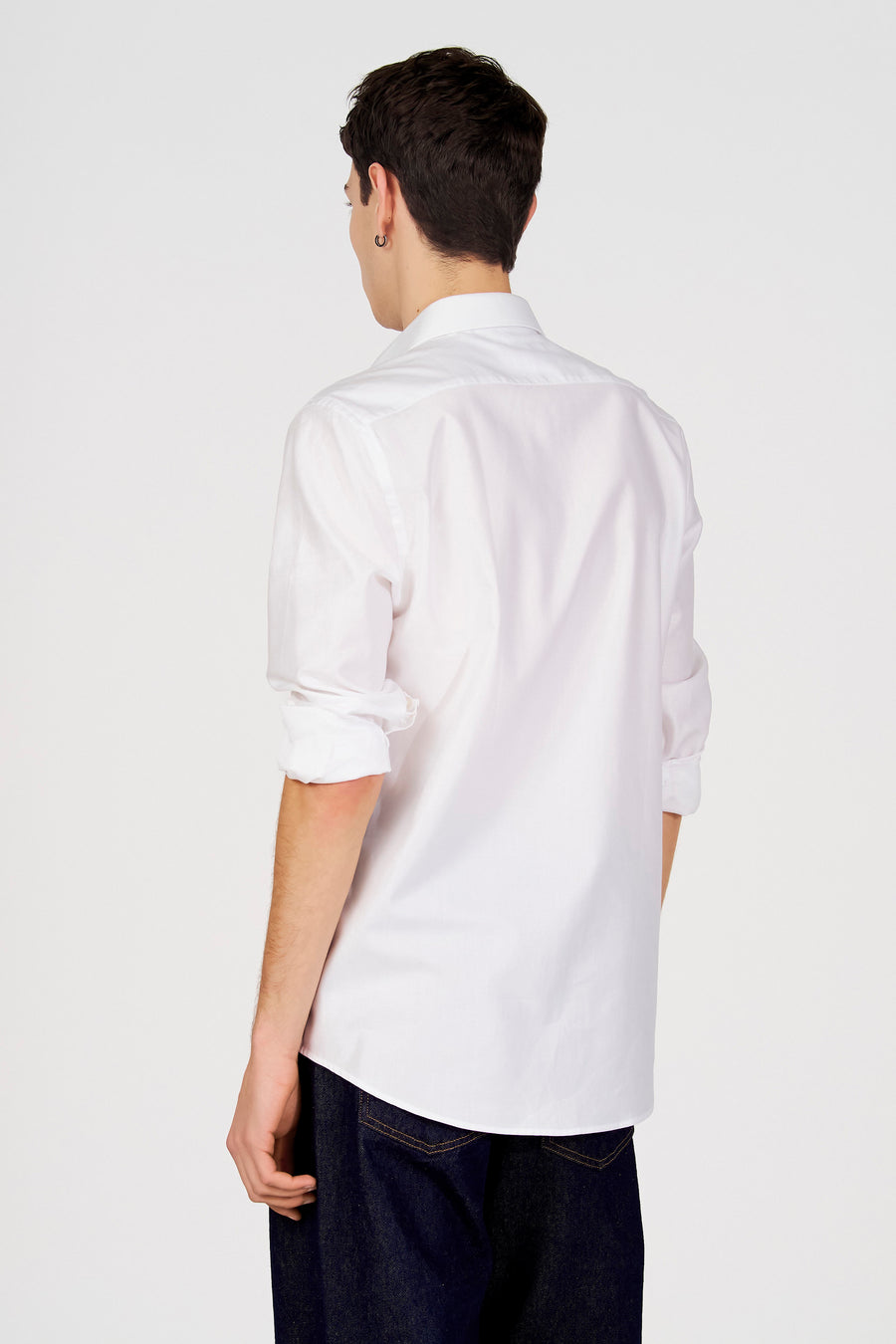 Chemise blanche à manches longues de Le Fabuleux Marcel de Bruxelles, vue de dos, associée à un jean foncé.