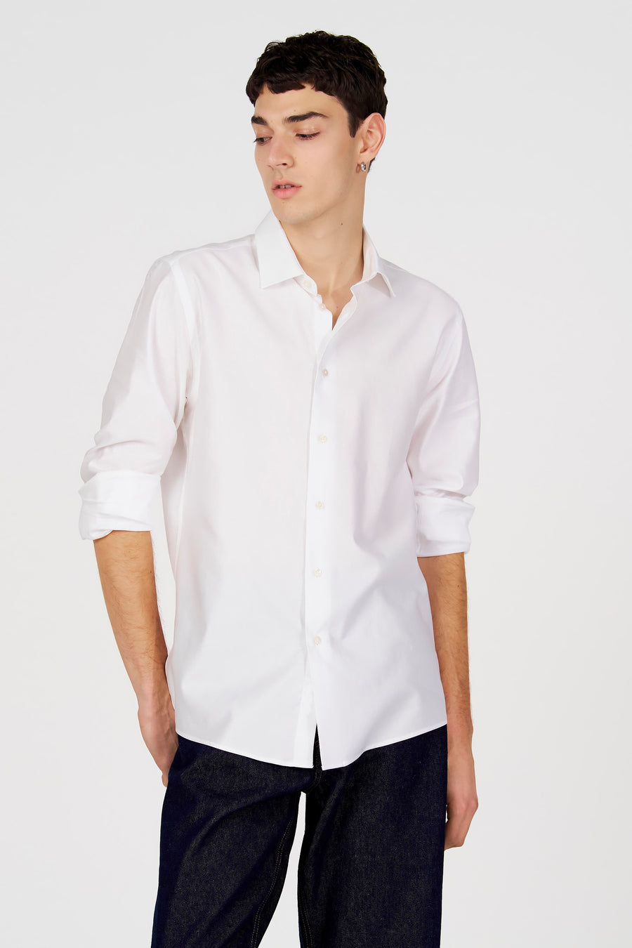 Chemise blanche à manches longues de Le Fabuleux Marcel de Bruxelles, portée avec un jean foncé.