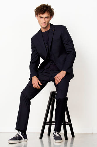 Blazer bleu de Le Fabuleux Marcel de Bruxelles avec un gêtement et une broche en or.