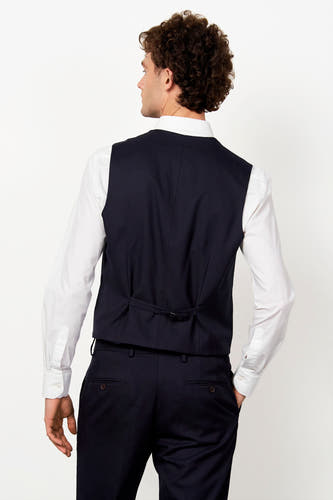 Blauw gilet van Le Fabuleux Marcel de Bruxelles, van achteren gezien, met verstelbare rugriem, gedragen over een wit overhemd.