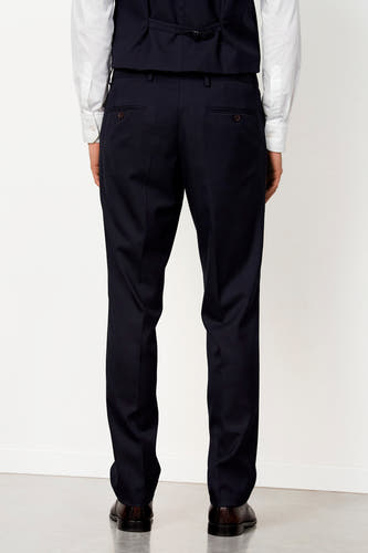 Donkerblauwe kostuumbroek van Le Fabuleux Marcel de Bruxelles, van achteren gezien, met knoopzakken, wit hemd en bruine schoenen.