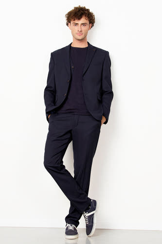 Pantalon de costume bleu de Le Fabuleux Marcel de Bruxelles, porté par un homme dans un costume assorti avec des baskets.