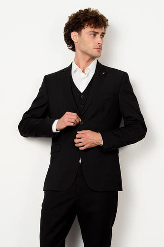 Zwarte blazer van Le Fabuleux Marcel de Bruxelles, met wit overhemd, gilet, reversspeld en knoopsluiting.