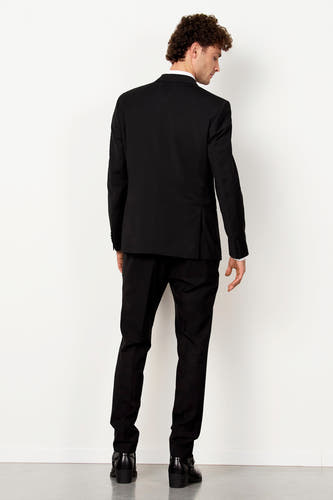 Blazer noir de Le Fabuleux Marcel de Bruxelles, avec une veste, un nœud papillon et des chaussures marrons.
