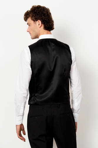 Zwart gilet van Le Fabuleux Marcel de Bruxelles met satijnen achterkant, gedragen op een wit overhemd en zwarte pantalon, gezien vanaf de achterkant.