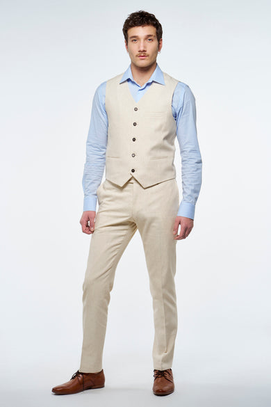 Man in beige pak met blauw overhemd en bruine schoenen.