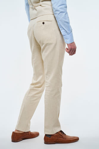 Pantalon beige Le Fabuleux Marcel de Bruxelles, avec une fermeture à glissière sur la poche arrière, associé à des chaussures en cuir marron.