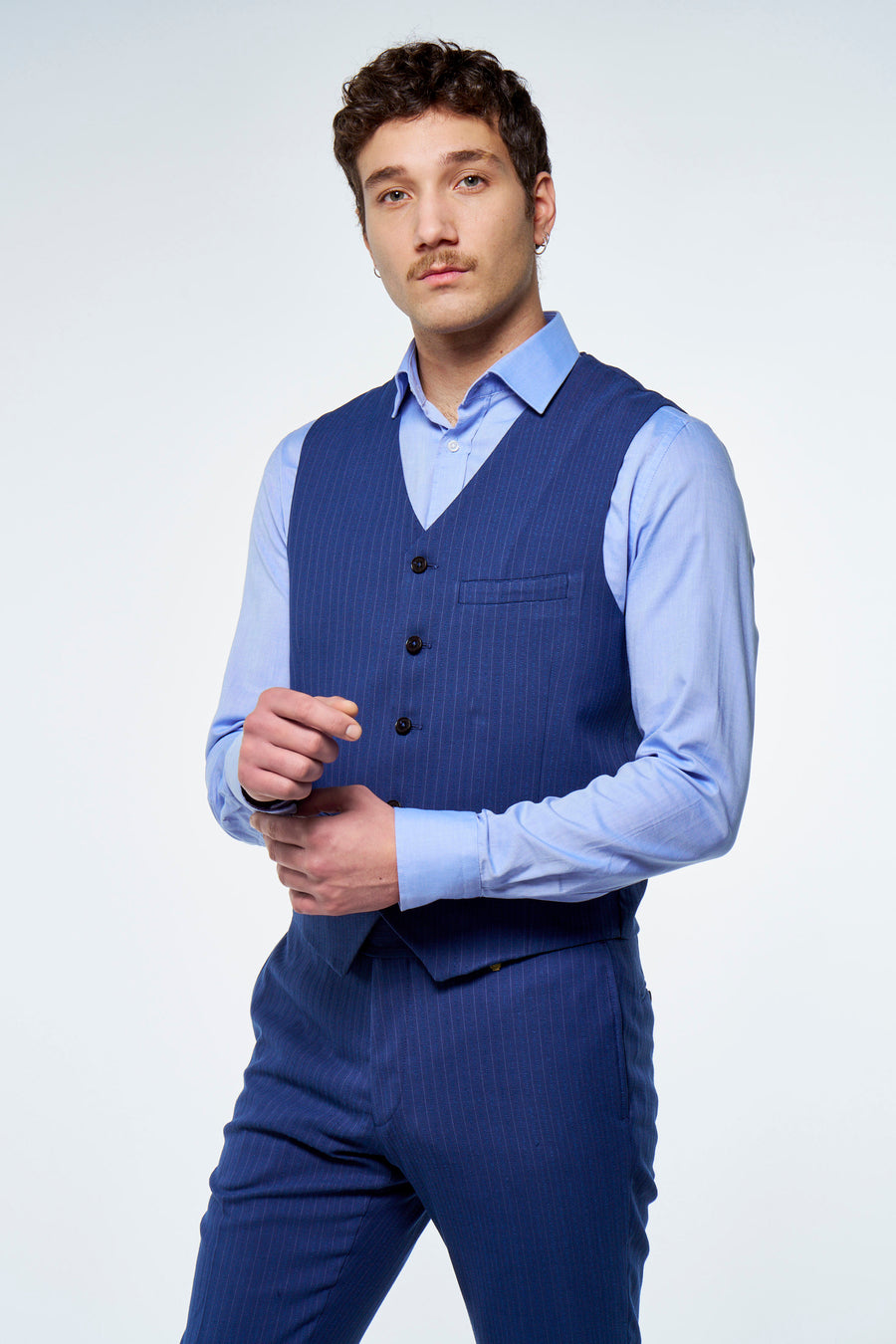 Gilet bleu à fines rayures de Le Fabuleux Marcel de Bruxelles, porté par un homme avec une chemise bleu clair et un pantalon assorti.