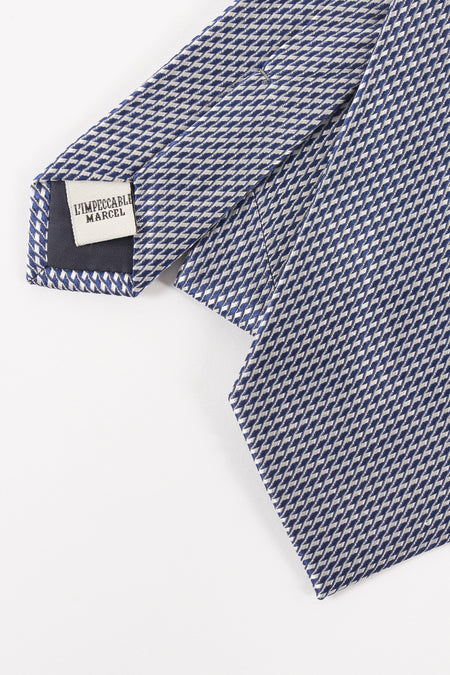 Doudou bleu de Le Fabuleux Marcel de Bruxelles, avec un fin motif géométrique et l'étiquette de marque visible.