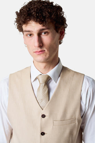 Blazer beige de Le Fabuleux Marcel de Bruxelles, avec un motif uni, porté avec une chemise blanche et une cravate.