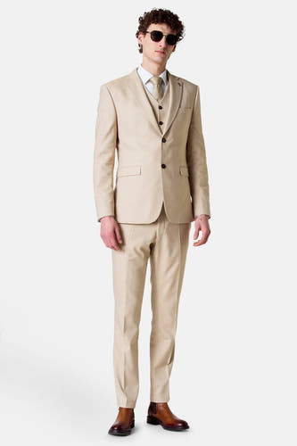 Gilet beige de Le Fabuleux Marcel de Bruxelles, porté sous un colbert et une pantalon assortis avec des chaussures marron.
