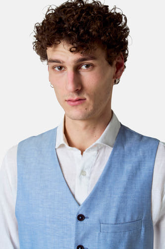 Gilet bleu de Le Fabuleux Marcel de Bruxelles, porté sur une chemise blanche à finition texturée.