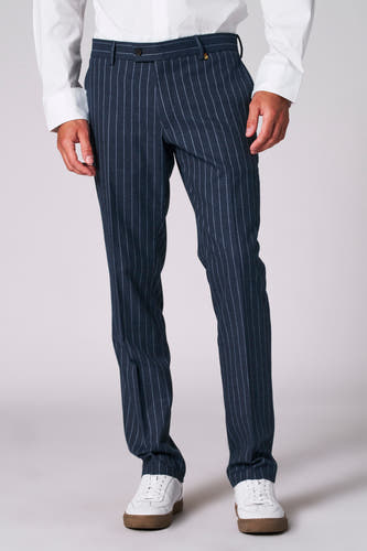 Pantalon de costume bleu avec une rayure blanche de Le Fabuleux Marcel de Bruxelles, porté avec un chemisier blanc et des baskets blanches.