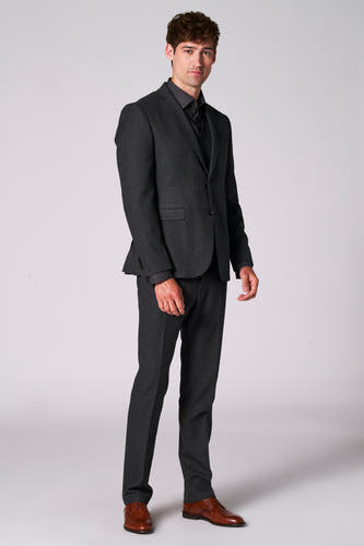 Blazer marron de Le Fabuleux Marcel de Bruxelles, porté avec un chemisier foncé et un pantalon coordonné, avec des chaussures marrons.