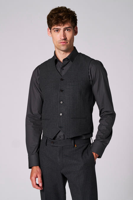 Gilet brun de Le Fabuleux Marcel de Bruxelles, avec une texture subtile et une ceinture ajustable à l'arrière, porté sur un chemisier noir.