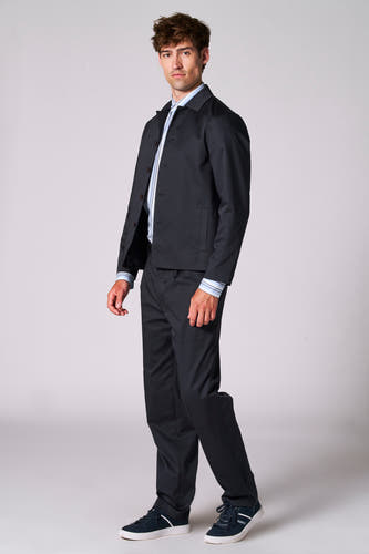 Blazer bleu de Le Fabuleux Marcel de Bruxelles, porté sur une chemise rayée et un pantalon noir, avec des chaussures en cuir bleu.