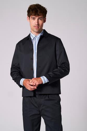 Blazer bleu de Le Fabuleux Marcel de Bruxelles, porté sur une chemise rayée, avec un pantalon coordonné.