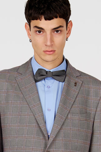 Blazer marron de Le Fabuleux Marcel de Bruxelles, à motif à carreaux, porté sur une chemise bleu clair avec un nœud papillon noir.