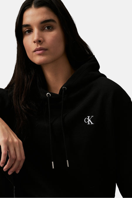 Gilet noir de Calvin Klein, avec un logo blanc sur la poitrine et des cordons noirs.