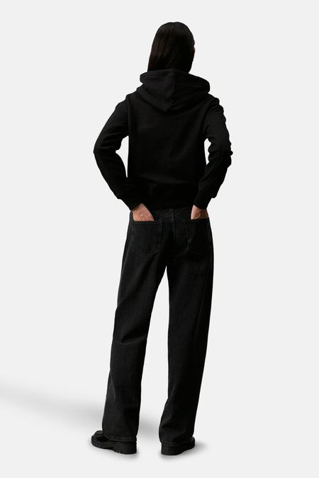 Pull-over noir de Calvin Klein, vu de l'arrière, avec des jeans noirs décontractés et des chaussures.