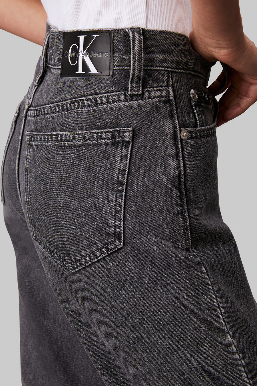 Jean droit gris de Calvin Klein Jeans, avec des surpiqures autour des poches et une étiquette de marque à l'arrière.