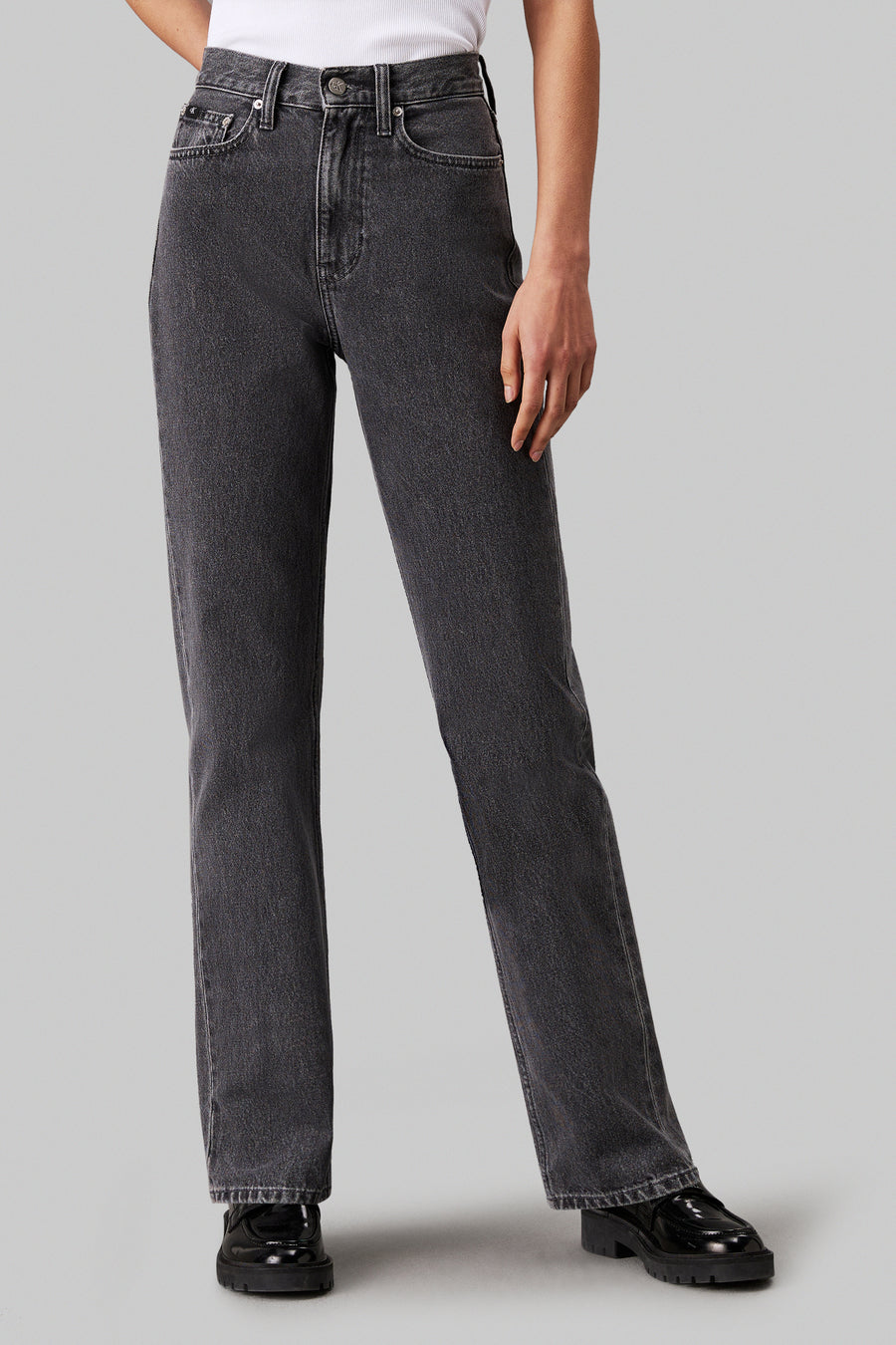 Jean droit de denim gris clair de Calvin Klein, avec une coupe classique et des chaussures noires.