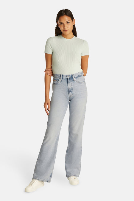 Jean bootcut en denim bleu clair de Calvin Klein, porté avec un t-shirt structuré et des baskets blanches.