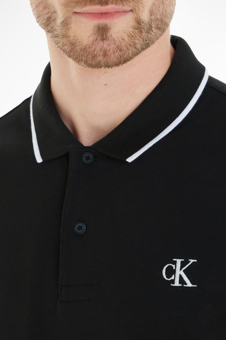 Polo noire Calvin Klein, à manches courtes et col liseré blanc, avec logo ck sur la poitrine.