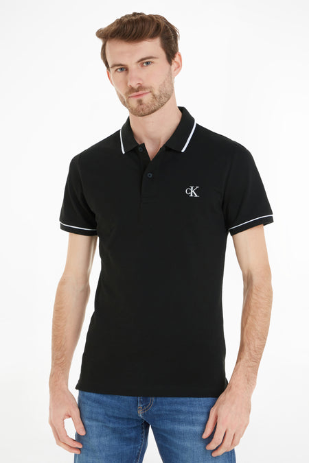 Polo noire Calvin Klein, à manches courtes et avec un passepoil blanc le long du col et des manches.