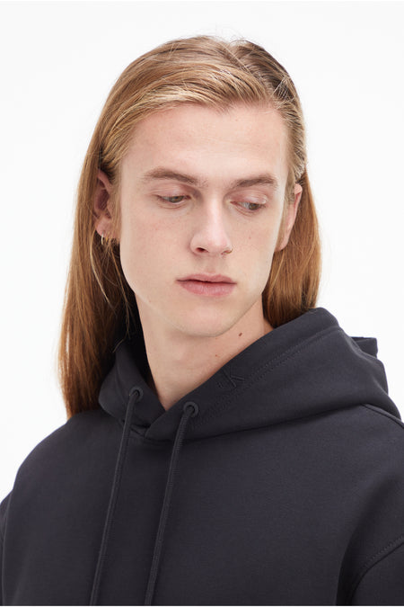 Sweat à capuche noir Calvin Klein avec capuche et cordon de serrage, gros plan sur l'épaule et le col.