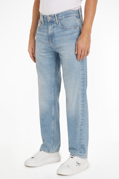 Jean droit en denim bleu clair de Calvin Klein, avec des poches et porté avec des baskets blanches.