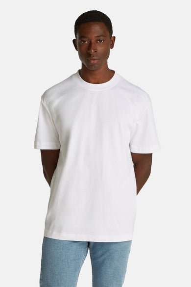 T-shirt blanc à manches courtes de Calvin Klein, avec une impression graphique sur le dos et des jeans bleu clair.