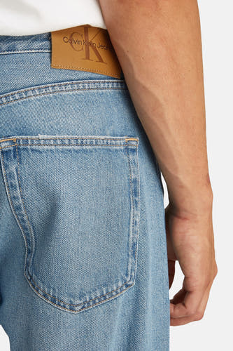 Jean droit en denim bleu marine de Calvin Klein, avec une étiquette en cuir de marque sur le dos.