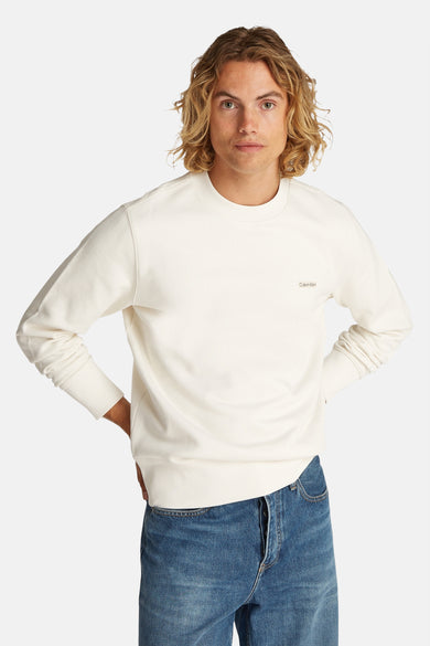 T-shirt écru de Calvin Klein avec col rond, associé à un jean bleu.