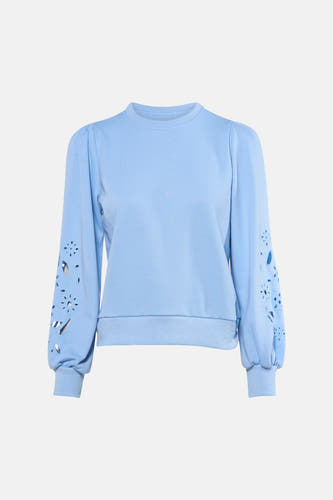Pull bleu de HAILYS, avec de longues manches bouffantes ornées de motifs floraux découpés, à combiner avec un jean ample et des baskets blanches.