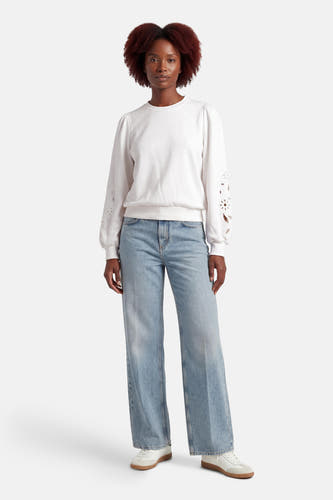 Pull blanc HAILYS, à manches longues avec détails floraux, combiné avec un jean ample et des baskets blanches.