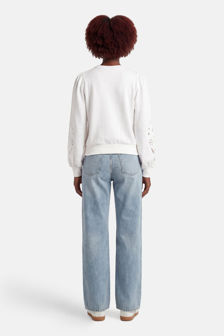 Pull blanc HAILYS à manches longues avec motif floral et jean bleu clair.
