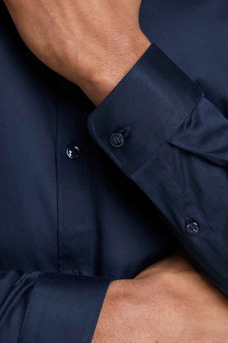 Chemise bleue à manches longues de PREMIUM by JACK & JONES, gros plan avec détail de boutons et bras croisés.
