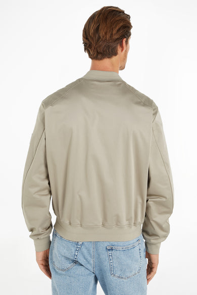 Veste courte écru de Calvin Klein, vue de dos, avec un col, des poignets et un ourlet côtelés, portée avec un jean clair.