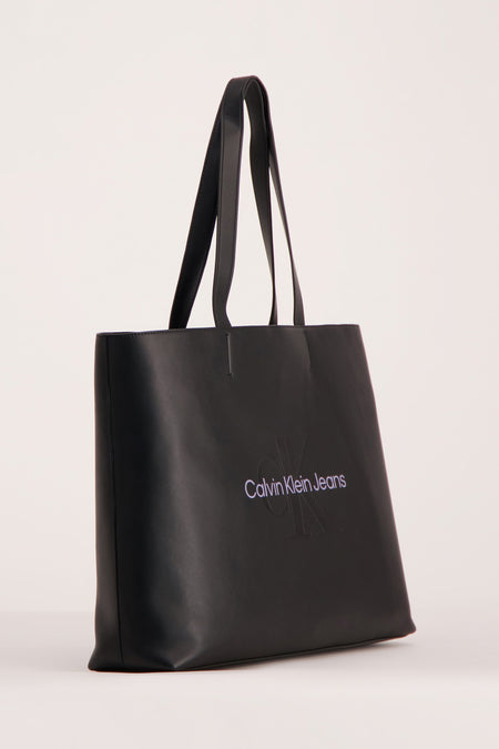 Sac à main noir de Calvin Klein Jeans avec imprimé logo sur l'avant, contre un fond uniforme.